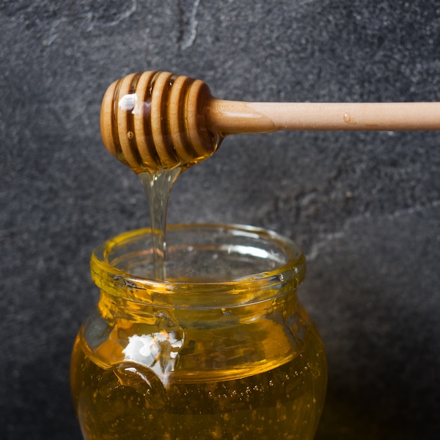 Un pot de miel liquide de fleurs de tilleul et un bâton avec du miel