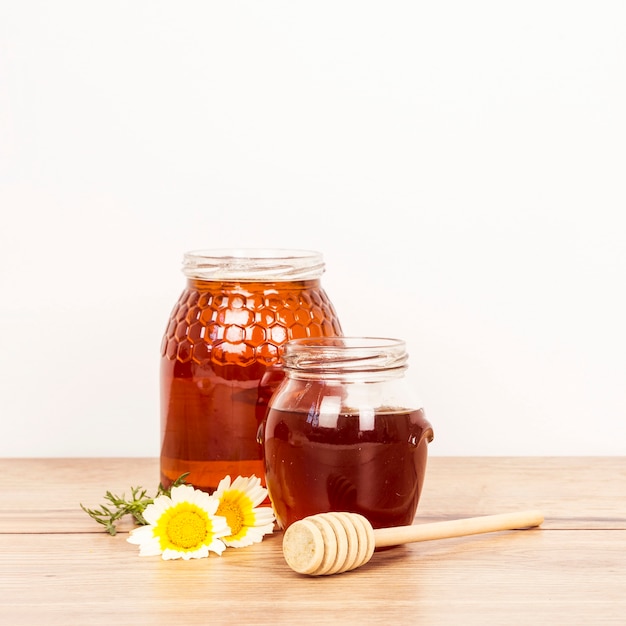 Photo pot à miel et louche de miel avec fleur blanche sur une surface en bois