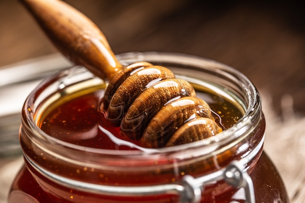 Pot de miel avec louche sur table en bois - gros plan.