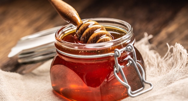 Pot de miel avec louche sur table en bois - gros plan.