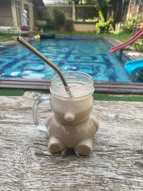 Un pot de milkshake avec une paille est posé sur une surface en béton.