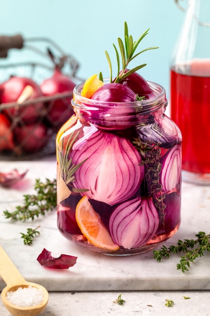 Un pot d'oignons rouges marinés sur un fond blanc Le concept de nourriture végétarienne fermentée