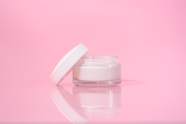 Pot ouvert de crème pour le visage sur fond rose