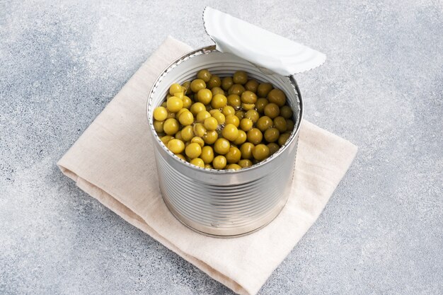 Photo pot ouvert en étain avec des pois en conserve sur un béton gris