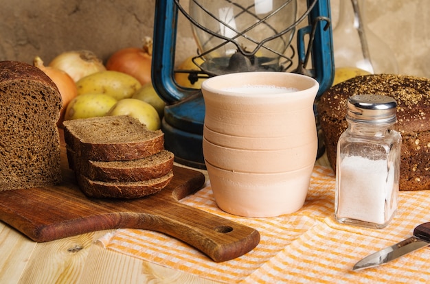 Pot de pain de seigle au lait une lanterne au kérosène légumes et sel sur la table