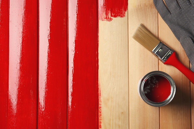 Pot de peinture et pinceau sur fond de bois peint en rouge