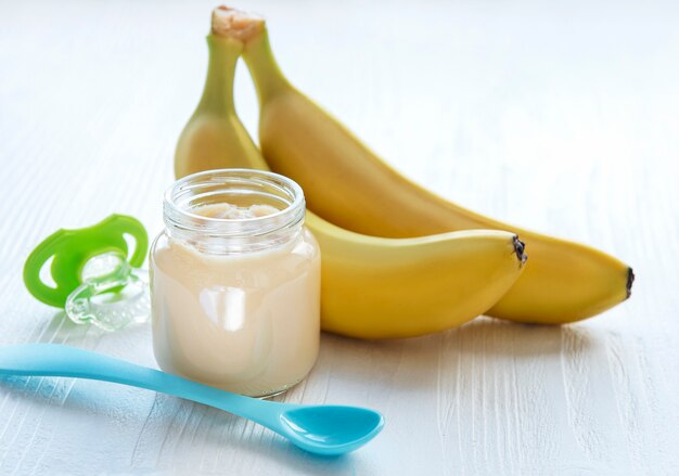 Pot de purée de banane et de bananes sur table en bois