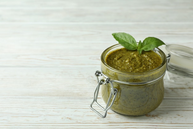 Pot de sauce pesto sur fond de bois blanc