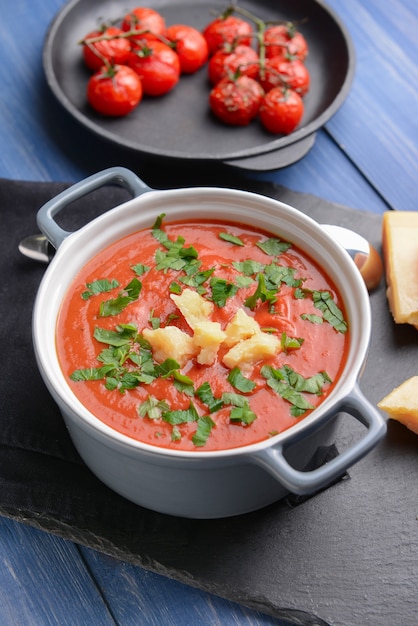 Pot de soupe à la crème de tomate savoureuse sur table en bois