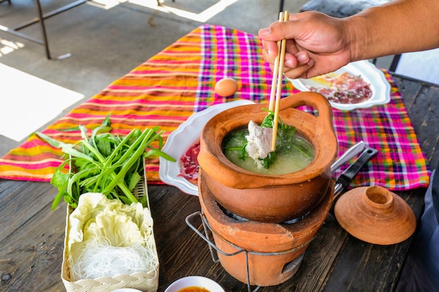 Pot en terre cuite thaïlandais traditionnel shabu shabu épicé, trempant la viande dans une soupe épicée bouillie.