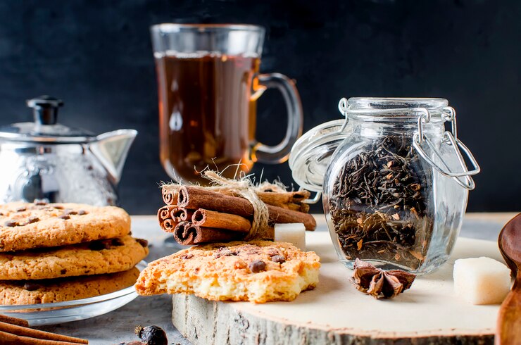 Pot à thé, biscuits maison et épices à thé sur fond sombre,