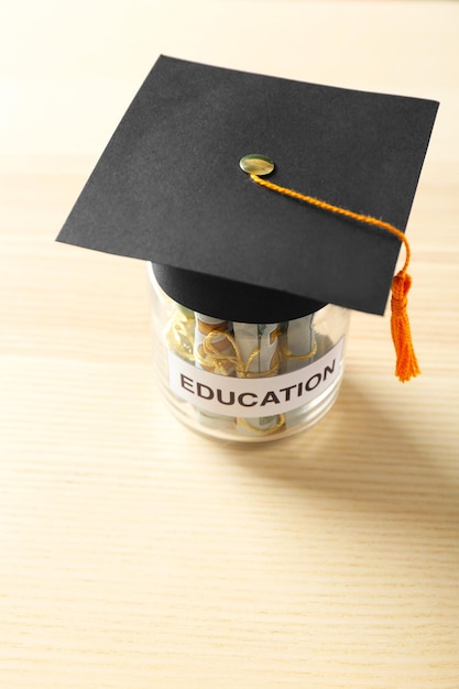 Pot en verre avec de l'argent pour l'éducation sur une table en bois