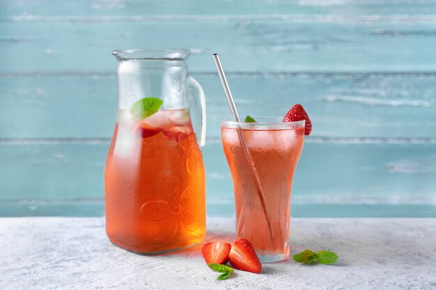 Un pot et un verre avec une boisson fraîche aux fraises d'été.