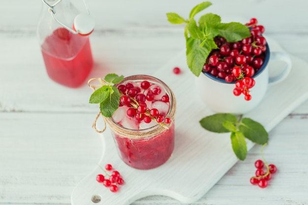 Pot en verre de boisson gazeuse de groseille rouge sur une table en bois blanc