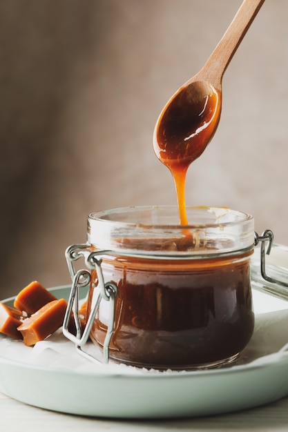 Pot en verre avec caramel salé et bonbons sur bois, espace pour le texte