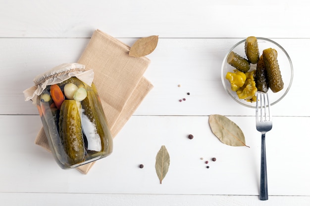 Pot de verre avec des concombres marinés sur fond blanc