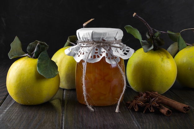 Pot en verre de confiture de coing maison avec des fruits frais sur la table