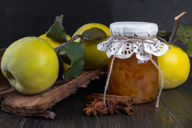 Pot en verre de confiture de coing maison avec des fruits frais sur la table