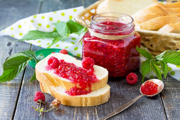 Pot en verre avec confiture de framboises et feuilles de menthe