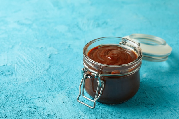 Pot en verre avec du lait concentré au caramel sur fond bleu