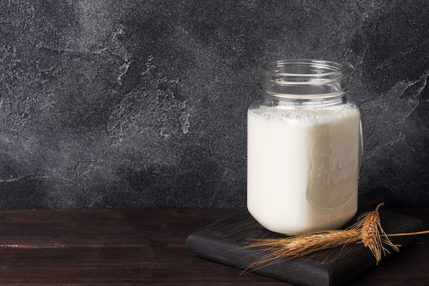 Pot en verre avec du lait sur un fond sombre