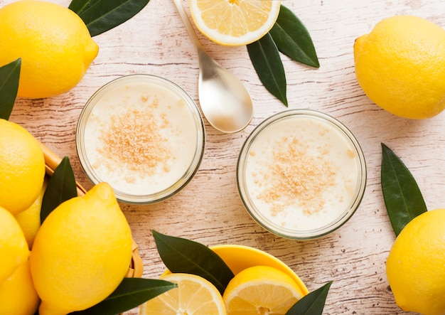 Pot en verre avec gâteau au fromage au citron avec des citrons frais sur bois