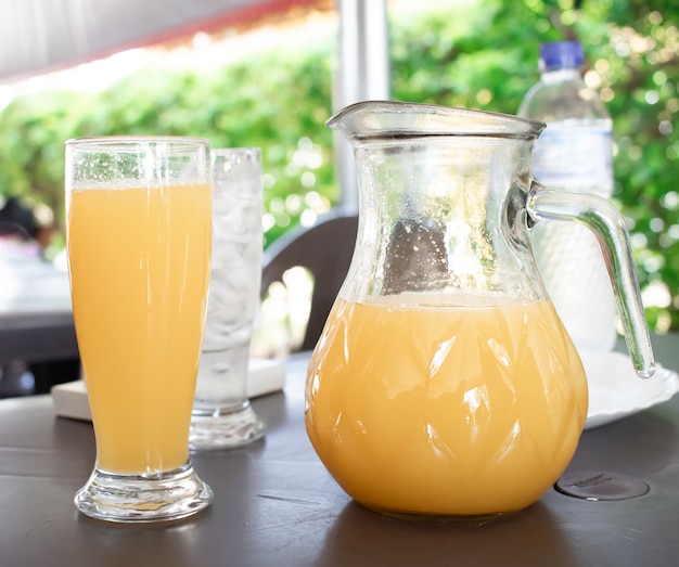 un pot en verre de jus d'orange sur une petite table à l'extérieur à la lumière du jour