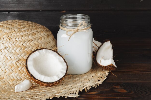 Pot de verre de lait de coco bouchent sur bois