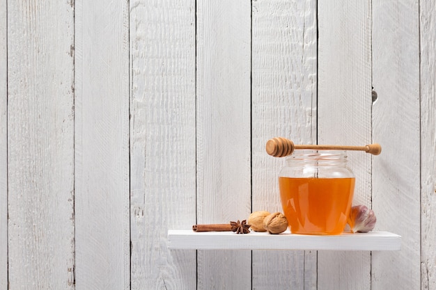 Pot en verre de miel sur fond d'étagère en bois