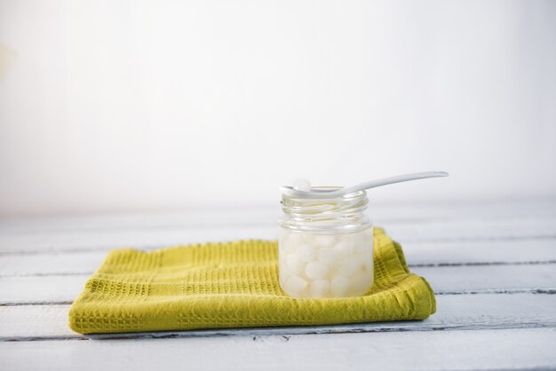 Photo pot de verre d'oignons marinés sur fond de bois blanc