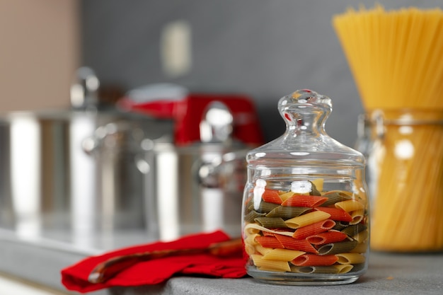 Pot en verre de pâtes sèches sur le comptoir de cuisine