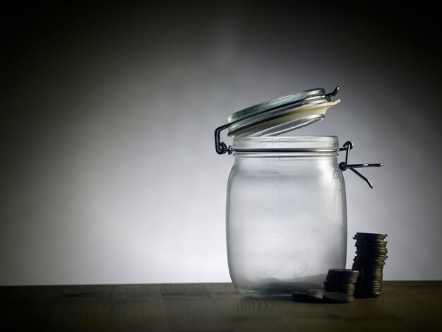 Un pot en verre avec une pile de pièces sur une table en bois