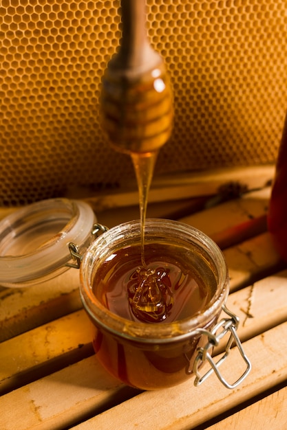 Photo pot en verre plein de miel avec une cuillère à miel