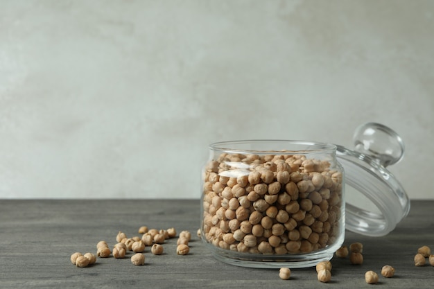 Pot en verre avec pois chiches frais sur table texturée gris