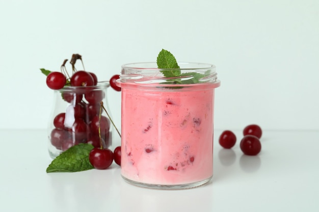 Pot en verre de smoothie aux cerises et ingrédients sur fond blanc