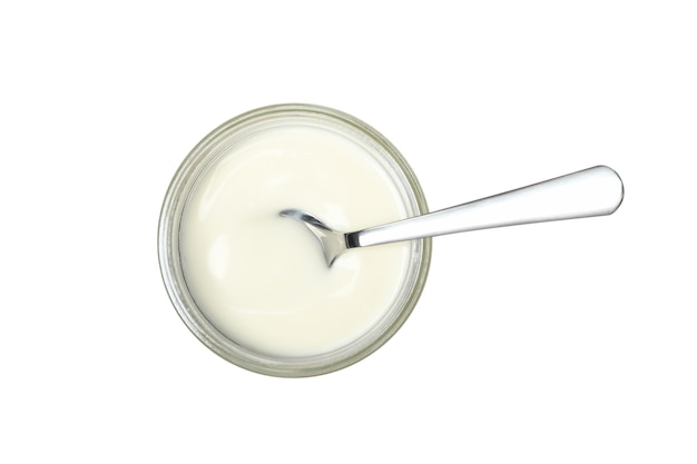 Pot en verre de yaourt à la crème sure et cuillère isolé sur blanc