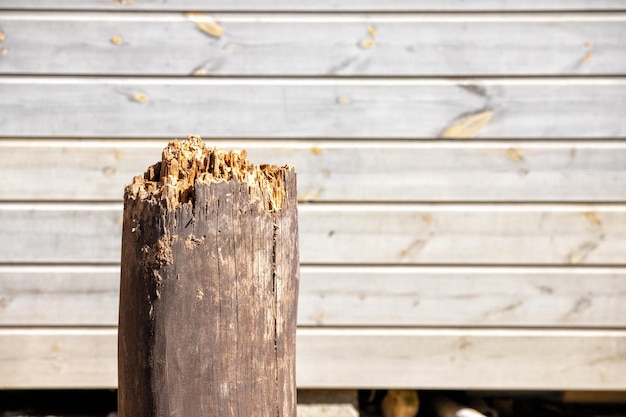 Un poteau de bois cassé contre un mur de clapboards