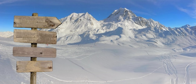 Poteau directionnel en bois avec flèche pointant vers la droite sur les pistes de ski en pic enneigé