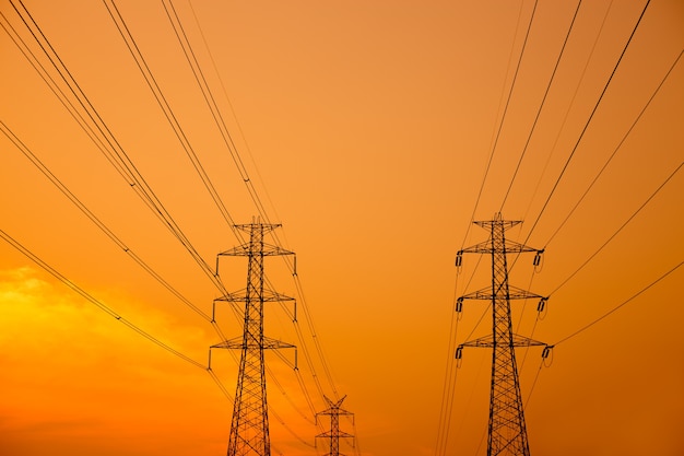 poteau électrique au coucher du soleil, poteau haute tension fond ciel orange au coucher du soleil