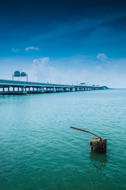 Un poteau métallique abandonné par un pont sur la mer contre le ciel
