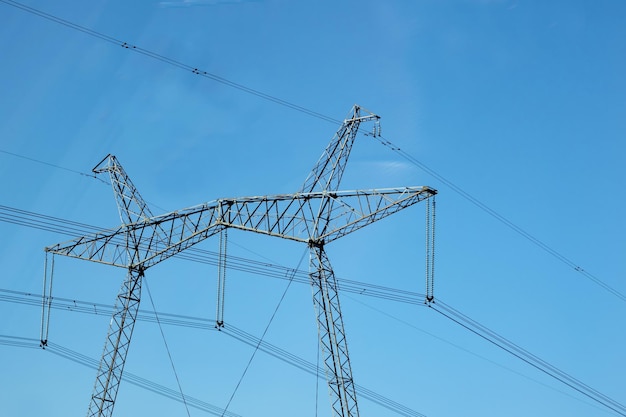 Un poteau de réseaux électriques et de fils contre le ciel bleu