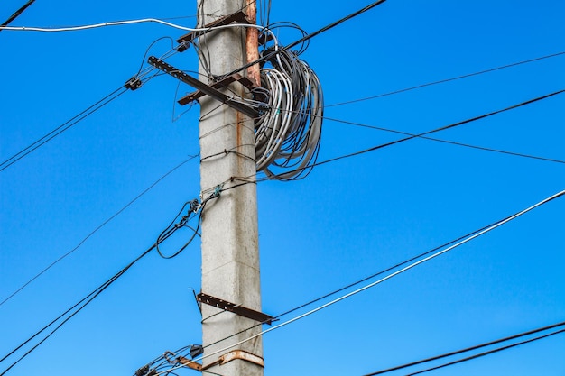 Poteau télégraphique électrique avec câbles et fils en désordre ciel bleu