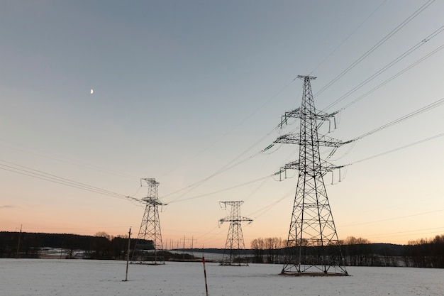 Poteaux électriques Photographiés En Hiver. Au Sol, La Neige Dérive Après Une Chute De Neige. Le Ciel En Arrière-plan Au Coucher Du Soleil