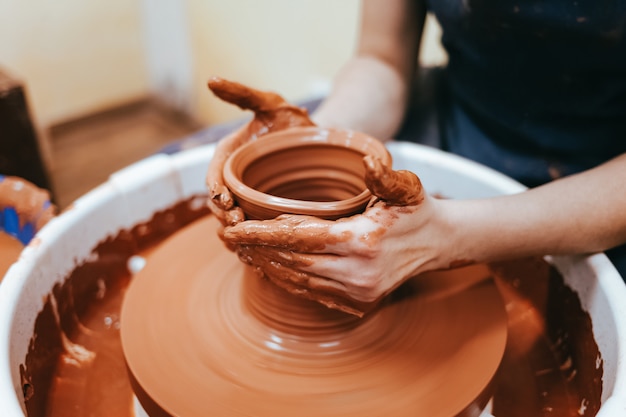 Un potier derrière le tour de potier forme de l'argile pour créer des plats en céramique