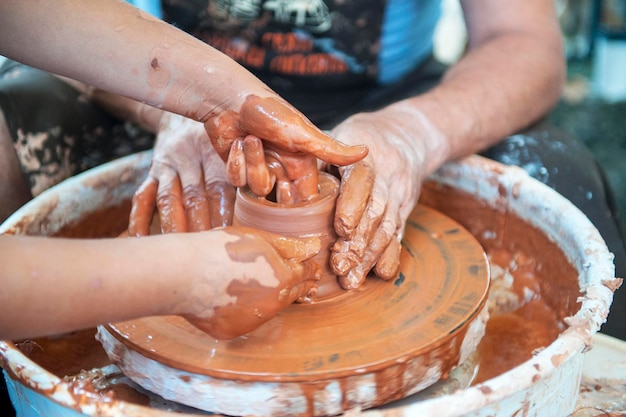 Le potier fabrique des plats de poterie sur un tour de potier. Le sculpteur en atelier fabrique des produits en argile en gros plan. Mains du potier.