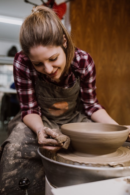 Potier femelle faisant de la poterie d'argile sur une roue de rotation