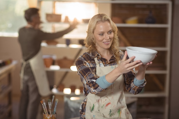 Potier vérifiant le bol dans l'atelier de poterie