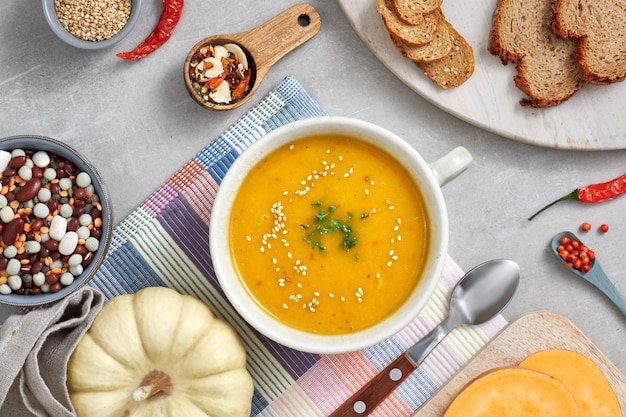 Potiron, haricots mélangés et soupe de crème de patate douce dans un bol en céramique, vue de dessus avec des ingrédients