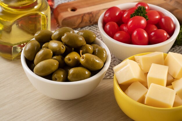 Pots d'apéritif avec du fromage, des olives et des tomates cerises.