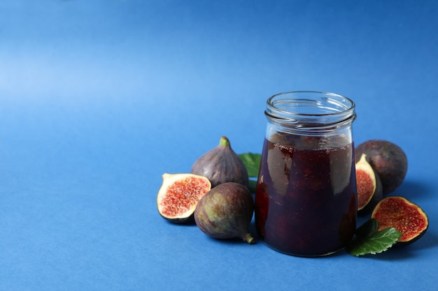 Pots avec confiture de figues et ingrédients sur fond bleu